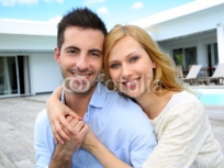 Cheerful_young_couple_sitting_in_front_of_modern_house.jpg